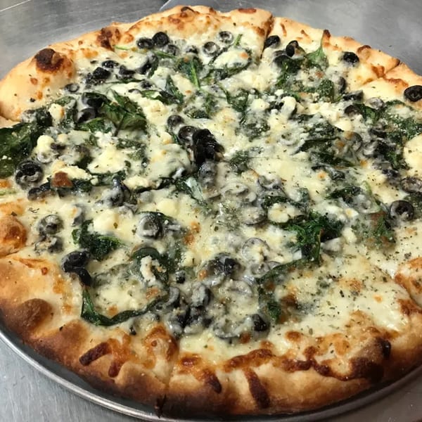 Venice Pizza's white pizza with spinach, black olives, and feta cheese on a metal pan.