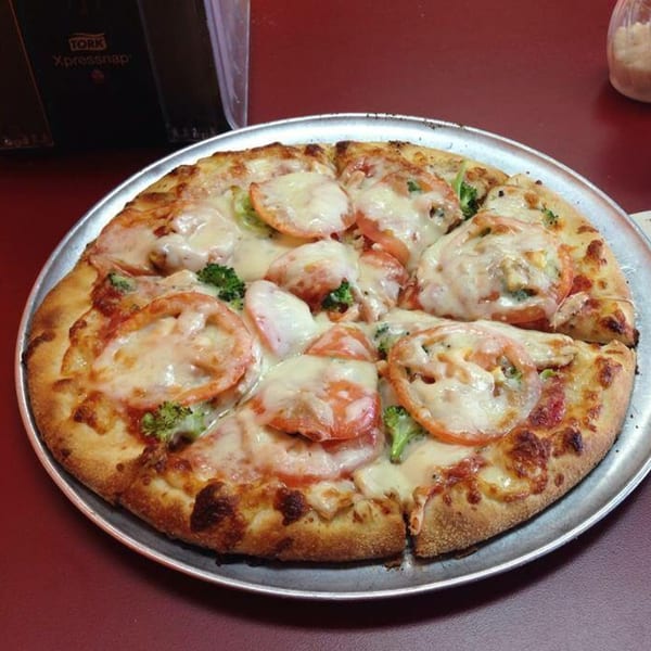 Venice Pizza's white pizza with tomatoes and broccoli, served on a metal pan.